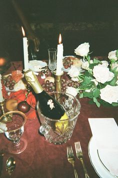 the table is set with wine, fruit and candles for an elegant dinner or celebration