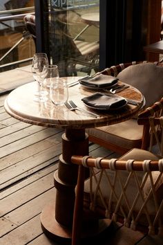 two chairs and a table on a wooden deck with water in the glass vases