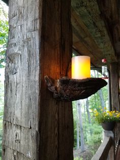 a candle is lit on the side of a wooden structure in front of some flowers