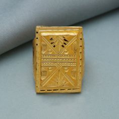 a gold ring sitting on top of a blue table next to a white cloth with black dots