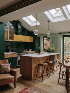 an open kitchen and living room with skylights above the dining table, bar stools