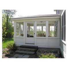 a small white house with windows and steps leading up to the front door that leads into the back yard