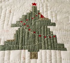 a quilted christmas tree with red stars on it's top and bottom corner