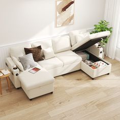 a living room with a white sectional couch and coffee table in the corner, on top of hard wood flooring