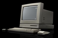 an old computer sitting on top of a black table next to a mouse and keyboard