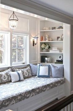 a window seat with pillows on it next to a bookshelf