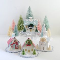 a group of small houses with trees in the background and snow on the ground around them