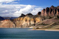 a lake surrounded by mountains under a cloudy blue sky