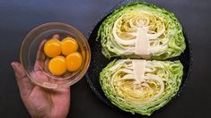 a hand holding a glass bowl filled with lettuce next to two halves of an egg