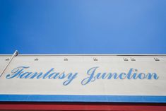 a sign on the side of a building that says fantasy junction under a blue sky