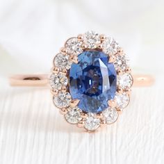 an oval shaped blue sapphire surrounded by small white diamonds in a rose gold halo setting