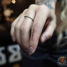 a woman's hand with a tiny cross tattoo on her left thumb and the word love written across it