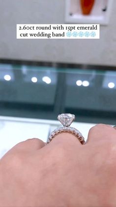 someone is holding their wedding ring in front of the mirror with an ad on it that says 2 00ct round with spt emerald cut wedding band