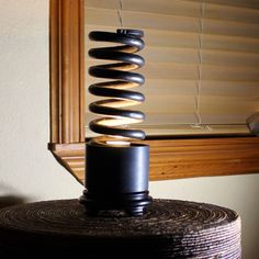 a black object sitting on top of a wooden table next to a window with blinds