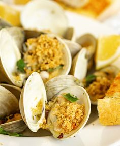 clams on a plate with bread and lemon wedges