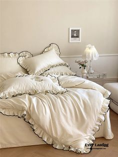 a bed with white sheets and black ruffles