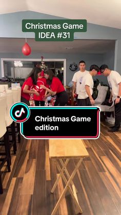 a group of people standing around a table with a christmas game sign on top of it