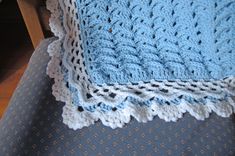 a blue crocheted blanket sitting on top of a chair