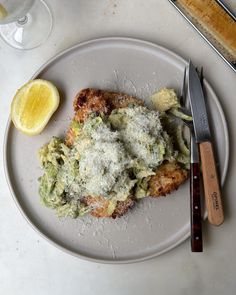 a white plate topped with food next to a knife and fork on top of a table