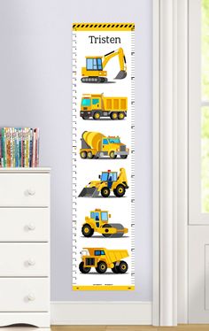 a growth chart with construction vehicles on it in a child's room next to a dresser