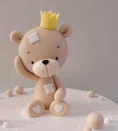 a teddy bear with a crown on top of it's head sitting on a cake