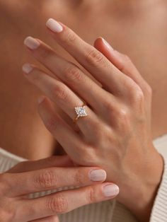 a woman's hand with a diamond ring on her left hand, wearing a sweater