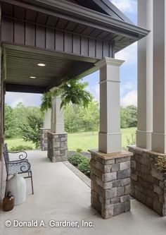 an outdoor patio with stone pillars and columns on the side of it, surrounded by lush green trees