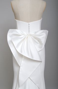 the back of a white wedding dress with a large bow on it's waist