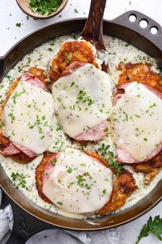 a skillet filled with meat covered in gravy and topped with parsley