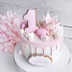 a pink and white cake with the number one on it