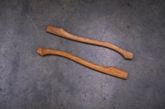 two wooden spoons sitting next to each other on top of a cement floor,