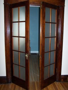 an open wooden door with frosted glass on the front and side doors to another room