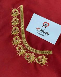 a red shirt with gold embroidery on the chest and collar, along with a white card that says art studio