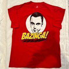 a red t - shirt with the words bazinga on it and a photo of a man's face