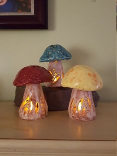 three small glass mushrooms sitting on top of a wooden table next to a framed photo