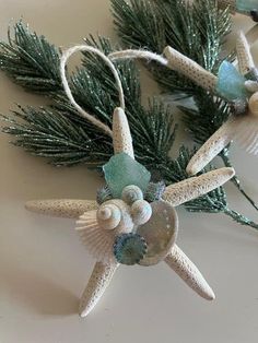 two starfish ornaments are sitting on a white surface next to pine branches and other decorations