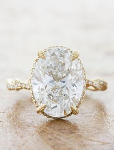 an oval cut diamond ring on top of a wooden surface