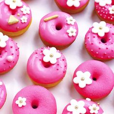 there are many pink donuts with white flowers on them and gold trimmings