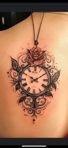 a woman's back with a rose and clock tattoo on it