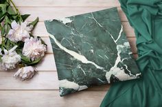 a green marbled pillow sitting on top of a wooden floor next to white flowers