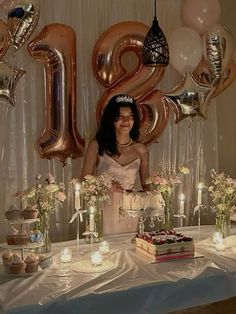 a woman standing in front of a table filled with balloons and cake on top of it