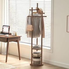 an open laptop computer sitting on top of a wooden shelf next to a coat rack