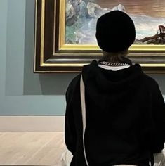 a person sitting in front of a painting with a pink heart drawn on it's back