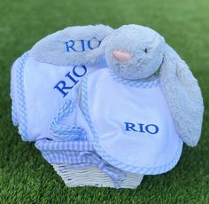 a stuffed bunny is sitting in a basket on the grass with his name written on it