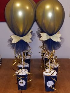 two gold and blue balloons are on top of some cupcakes with streamers