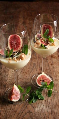 two wine glasses filled with dessert and garnished with figs, leaves and nuts