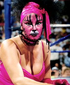 a woman in pink is sitting on the ground with her face painted like a tiger