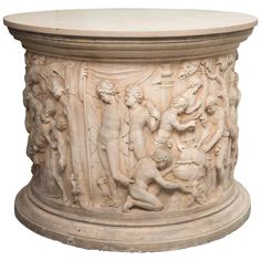 a white marble pedestal with carvings on it's sides and people around the base