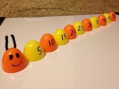 an orange and yellow caterpillar with numbers on it sitting in front of a white board