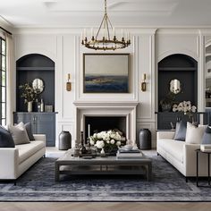 a living room filled with furniture and a fire place under a chandelier above a fireplace